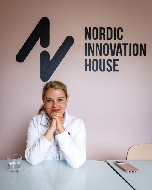 Swenode AI's Director Minna Sandberg in front of a logotyp of Nordic Innovation House