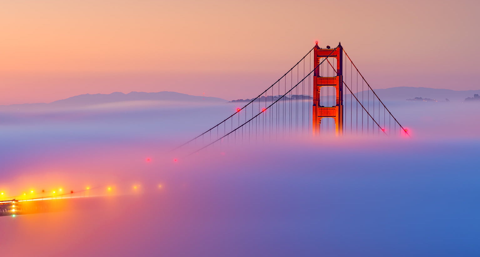 Golden gate bridge with fog in the lower parts. Purple and very scenic image.